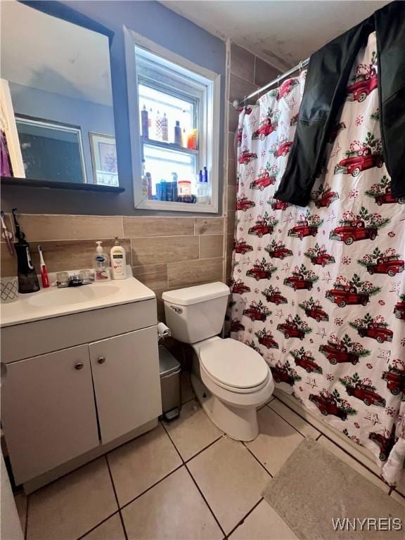 bathroom with tile walls, vanity, toilet, and tile patterned floors