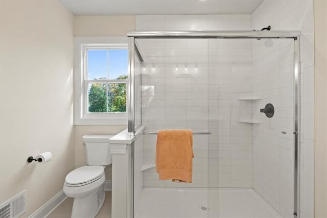 bathroom featuring a shower with door and toilet