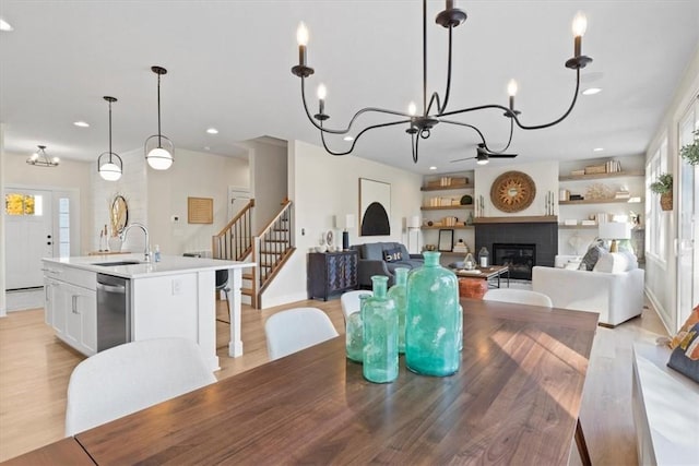 dining room featuring ceiling fan with notable chandelier, light hardwood / wood-style flooring, and sink