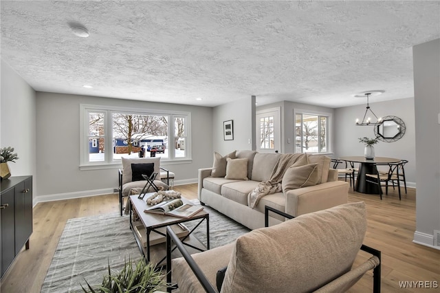 living room featuring light wood-type flooring, a textured ceiling, and a notable chandelier