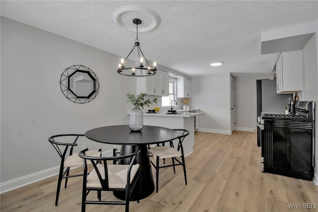 dining space with a notable chandelier, light wood-type flooring, and a textured ceiling