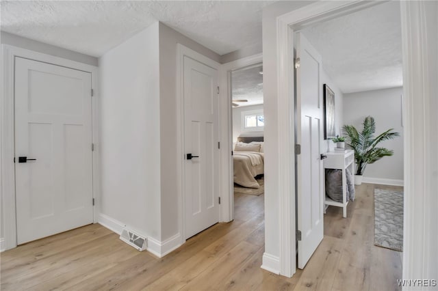 hallway featuring light hardwood / wood-style floors and a textured ceiling