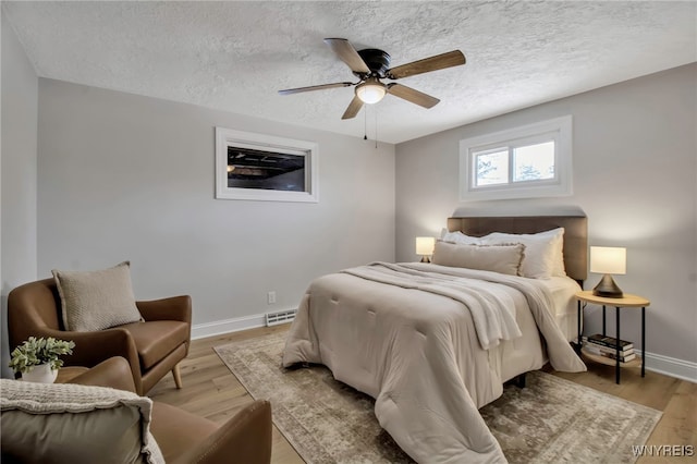 bedroom with ceiling fan, light hardwood / wood-style floors, and a textured ceiling