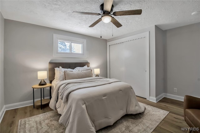 bedroom featuring hardwood / wood-style floors, a closet, ceiling fan, and a textured ceiling