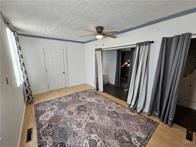 bedroom with hardwood / wood-style floors, ceiling fan, a textured ceiling, and ornamental molding