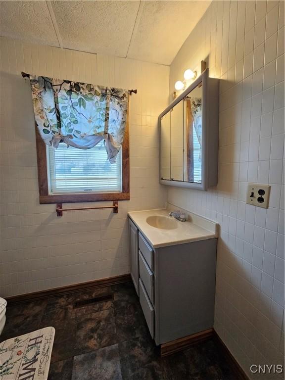 bathroom featuring toilet, a textured ceiling, tile walls, and vanity