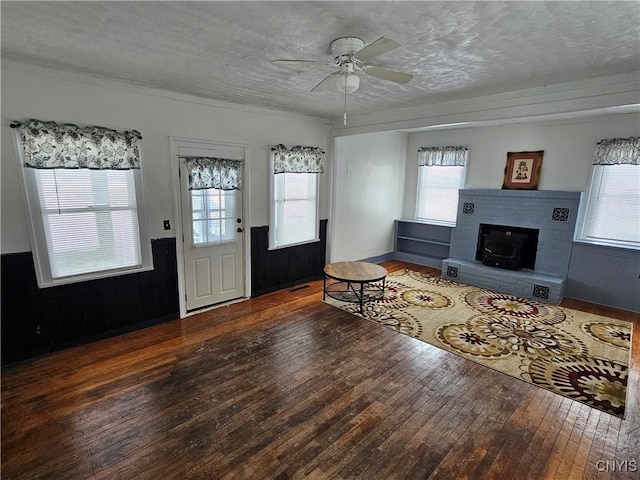 unfurnished living room featuring ceiling fan, a wealth of natural light, dark hardwood / wood-style flooring, and a textured ceiling