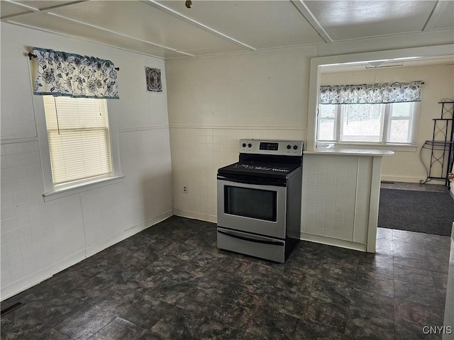 kitchen featuring stainless steel electric stove and tile walls