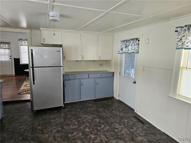 kitchen featuring white cabinetry, tile walls, and stainless steel refrigerator