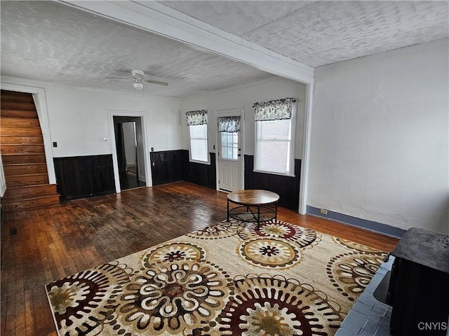 interior space with a textured ceiling, ceiling fan, wood walls, and dark hardwood / wood-style floors