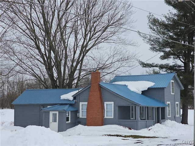 view of front of home with a chimney and metal roof