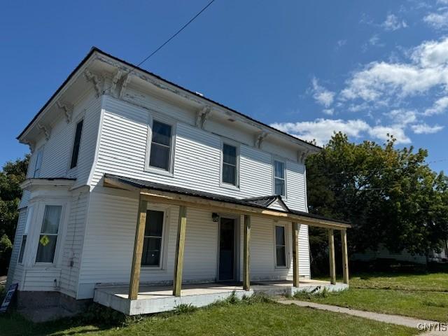 view of front of home featuring covered porch and a front lawn