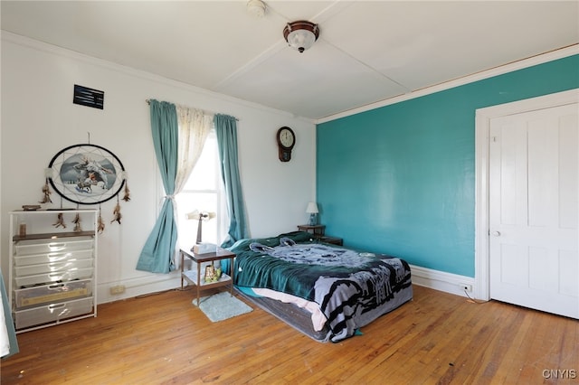 bedroom with hardwood / wood-style floors and ornamental molding