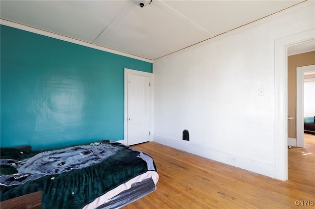 bedroom with hardwood / wood-style flooring and ornamental molding