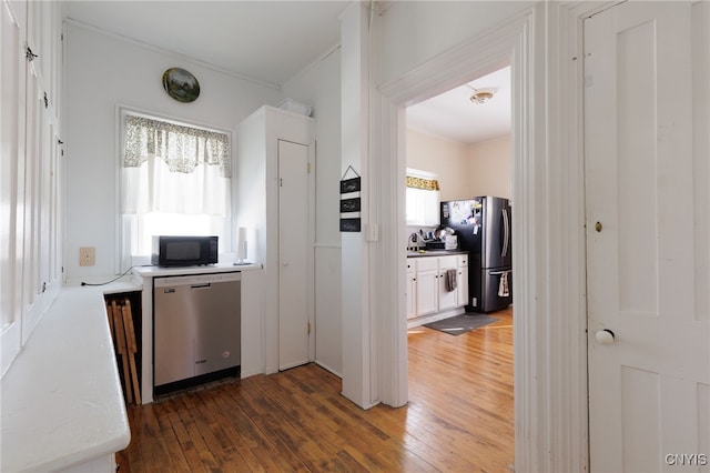 interior space featuring appliances with stainless steel finishes, ornamental molding, dark wood-type flooring, and sink