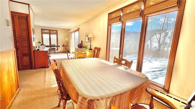 carpeted dining space with ornamental molding and a baseboard heating unit