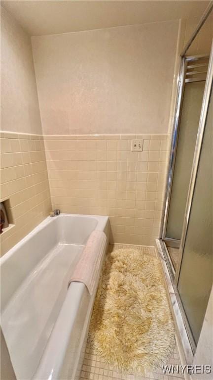 bathroom featuring tile walls, independent shower and bath, and tile patterned floors