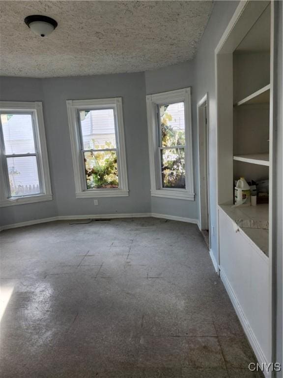 spare room with a textured ceiling, a wealth of natural light, and built in features