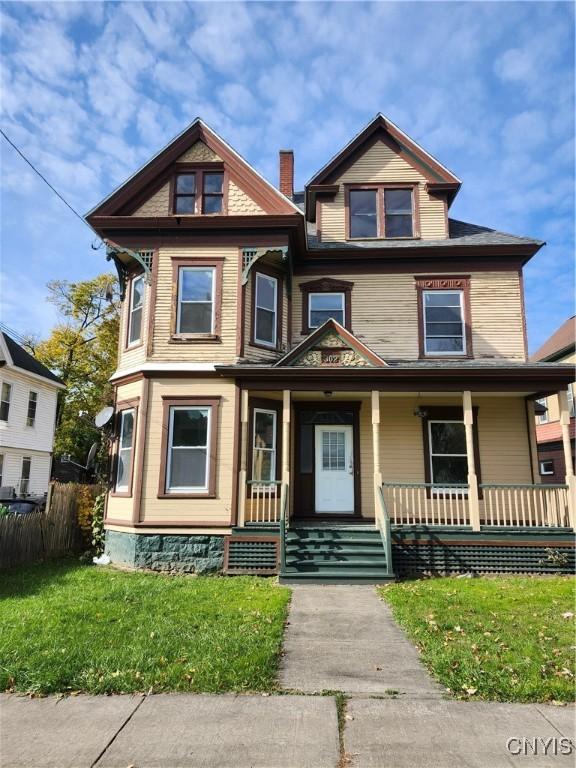 victorian home featuring covered porch and a front lawn