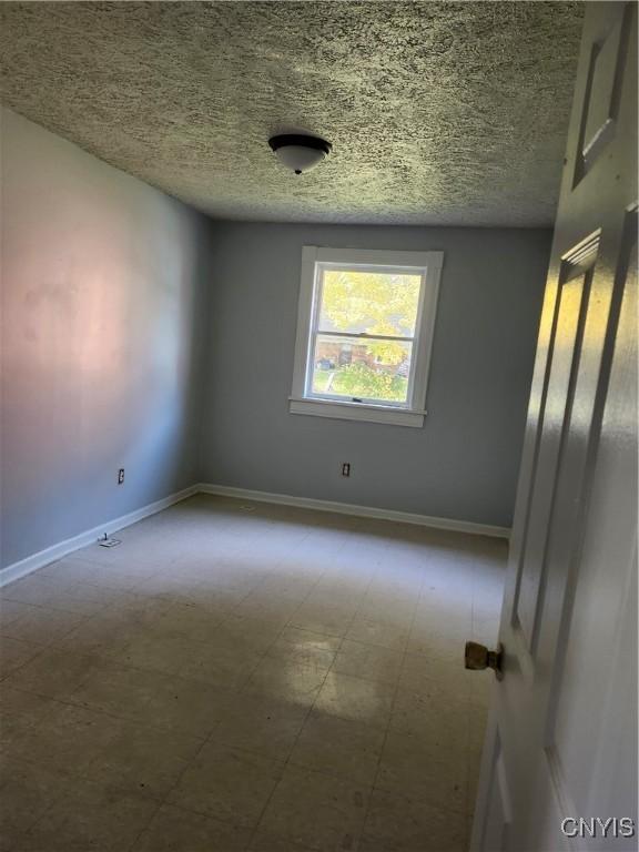 unfurnished room with a textured ceiling