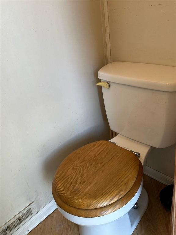 interior details featuring wood-type flooring and toilet