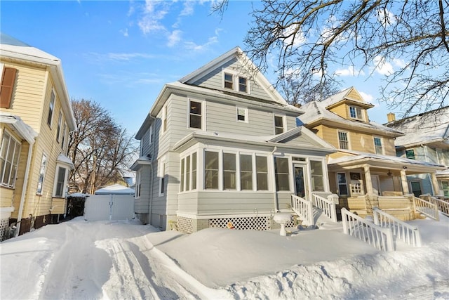 snow covered property with covered porch and a sunroom