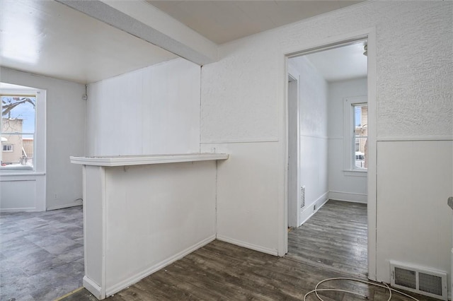 interior space featuring a wealth of natural light, dark hardwood / wood-style flooring, and beamed ceiling