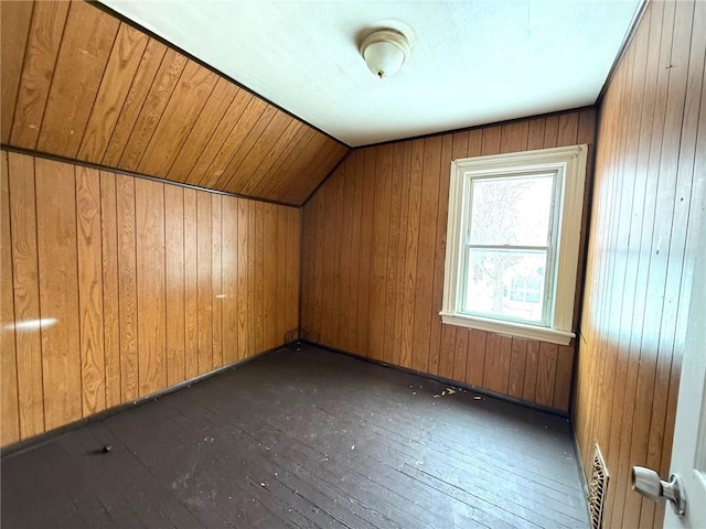 additional living space with dark hardwood / wood-style floors, vaulted ceiling, and wood walls