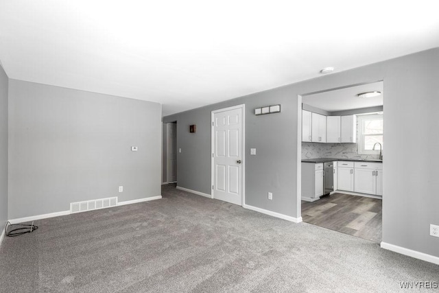 unfurnished living room with sink and light colored carpet