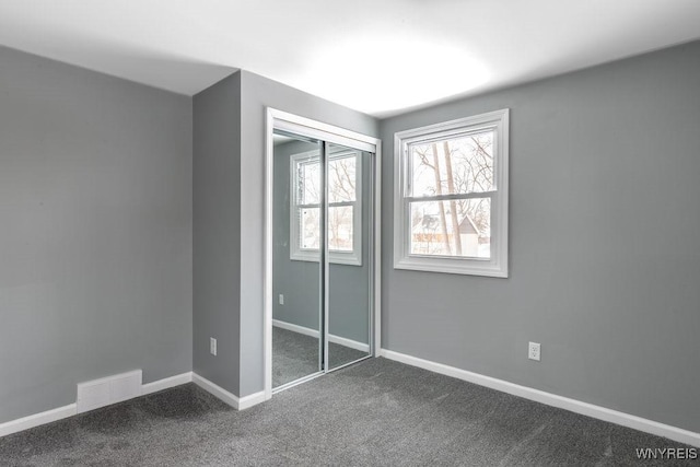 unfurnished bedroom featuring a closet and dark colored carpet