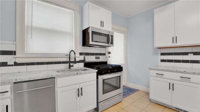 kitchen featuring appliances with stainless steel finishes, sink, light tile patterned floors, white cabinets, and tasteful backsplash