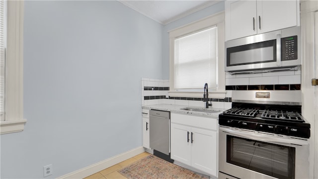 kitchen with sink, backsplash, light stone counters, stainless steel appliances, and white cabinets