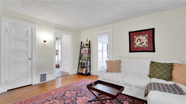 living room featuring light hardwood / wood-style flooring and a textured ceiling