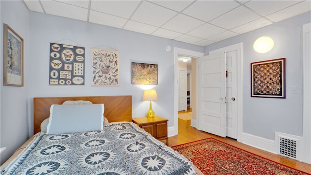 bedroom featuring a drop ceiling and wood-type flooring