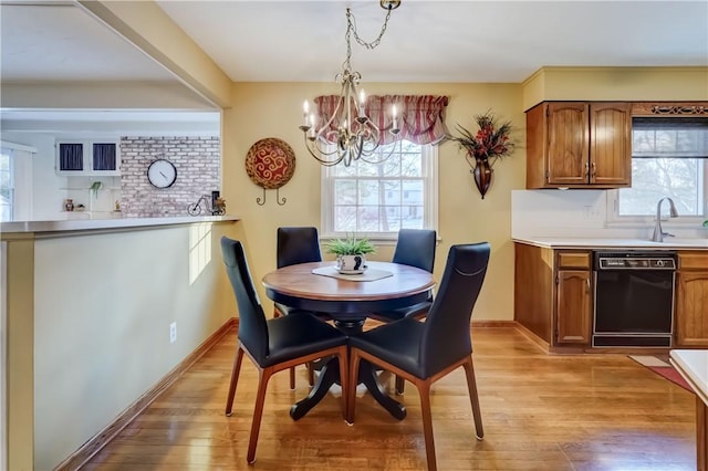 dining space featuring sink, light wood-type flooring, and a chandelier