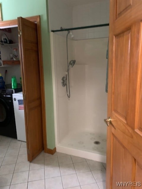 bathroom with tile patterned flooring, a shower stall, and washer / clothes dryer