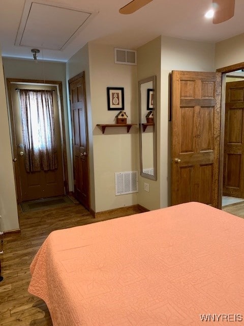 bedroom featuring visible vents, attic access, ceiling fan, and wood finished floors