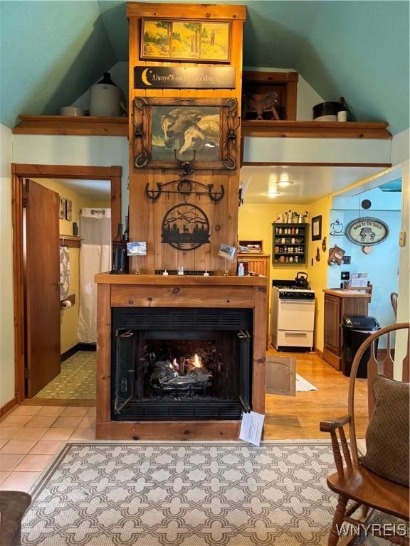 living area with a lit fireplace and lofted ceiling