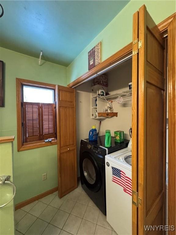 laundry area featuring baseboards, light tile patterned flooring, laundry area, and washing machine and clothes dryer