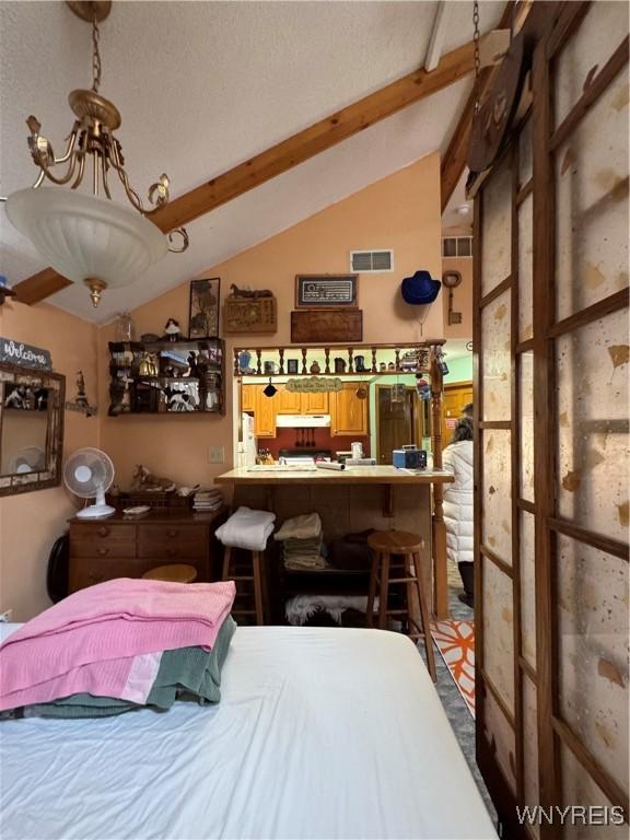 bedroom featuring visible vents, lofted ceiling with beams, and an inviting chandelier