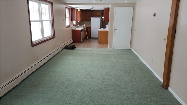 interior space with sink, stainless steel dishwasher, white fridge, a baseboard radiator, and light carpet