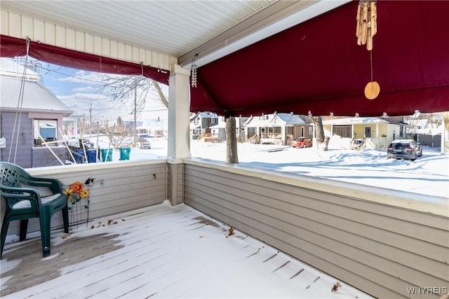 snow covered deck featuring covered porch