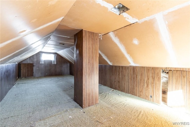 additional living space featuring light carpet, vaulted ceiling, and wooden walls