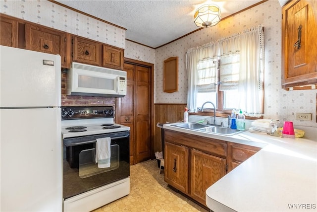 kitchen with sink, white appliances, crown molding, and a textured ceiling