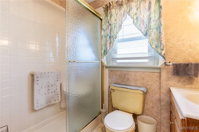 bathroom featuring toilet, vanity, and a shower with shower door