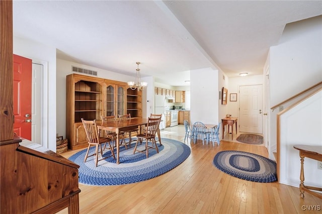 dining room featuring light wood-type flooring and an inviting chandelier