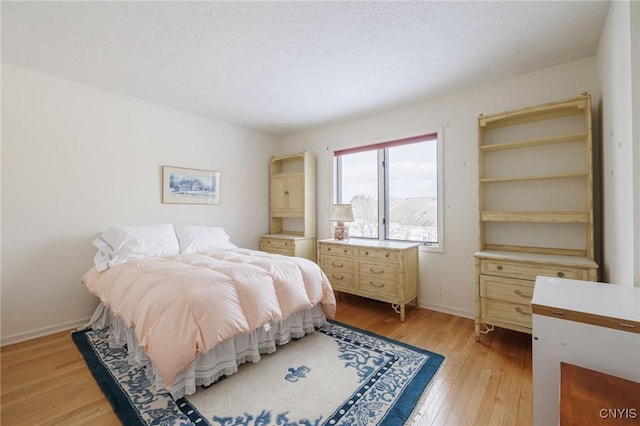 bedroom with a textured ceiling and light hardwood / wood-style floors