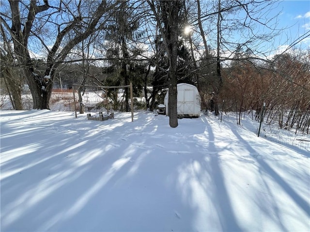 snowy yard featuring a shed