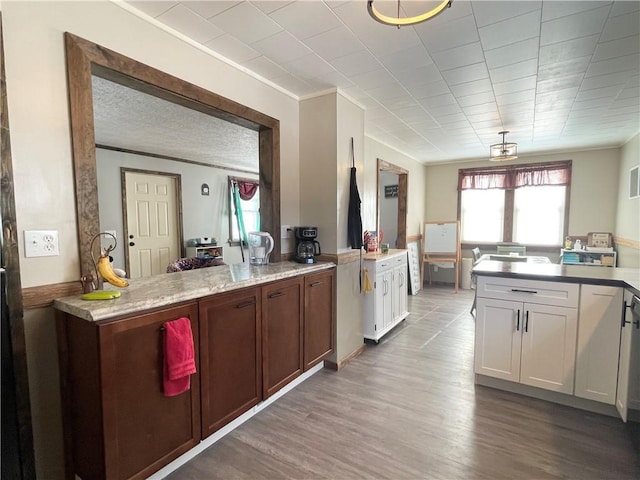 kitchen featuring crown molding, light hardwood / wood-style flooring, white cabinetry, and light stone countertops