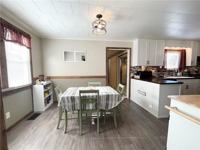 dining space featuring sink, crown molding, and wood-type flooring